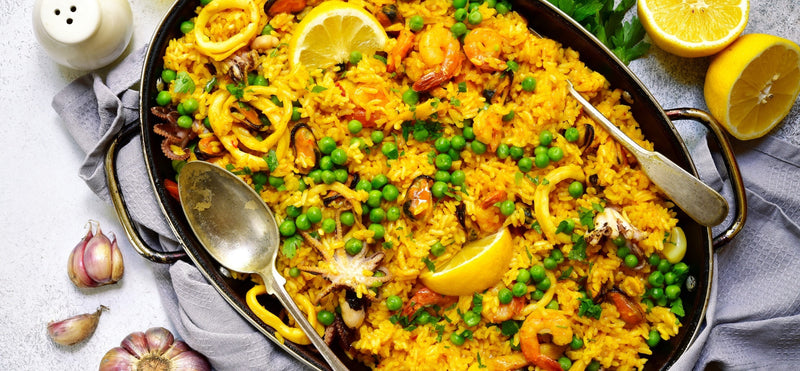 Authentic Spanish seafood paella with prawns, mussels, calamari, peas and lemon