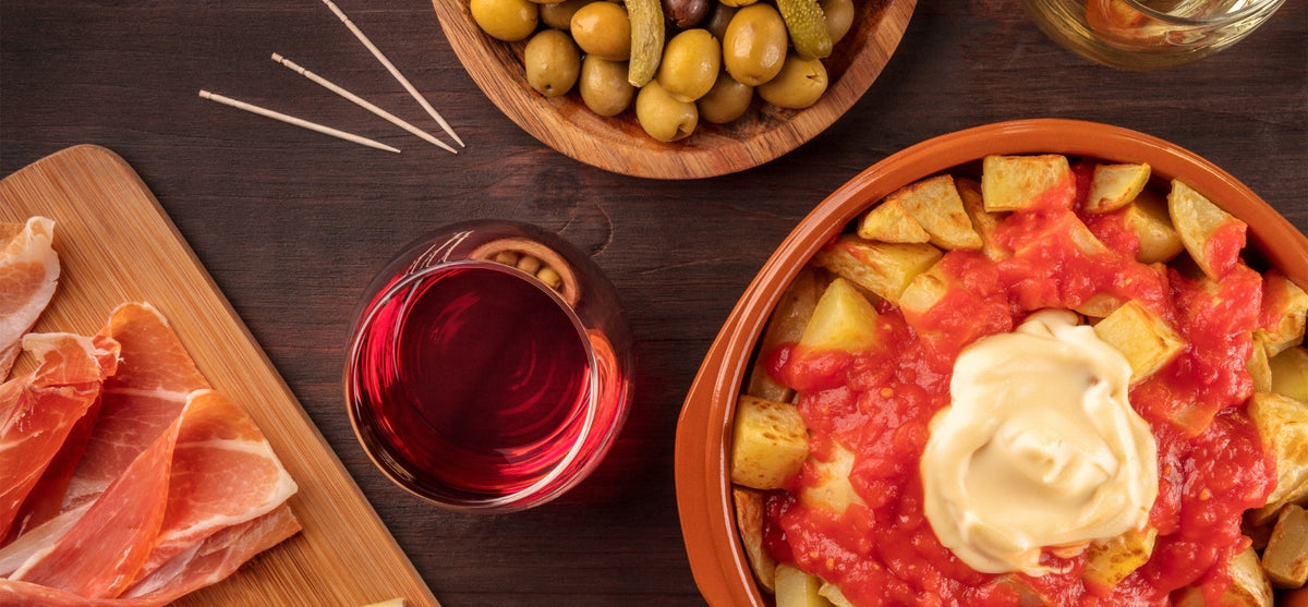 Patatas bravas with tomato sauce, aioli, olives, ham and red wine