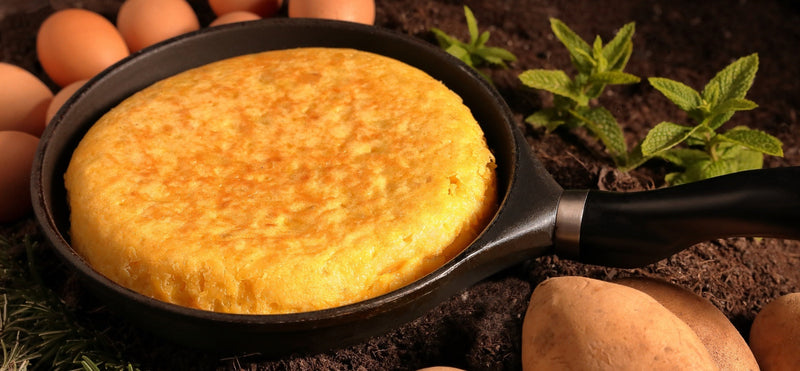 Spanish potato omelette in a black skillet with eggs and potatoes